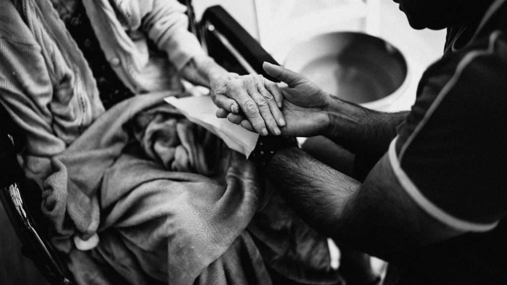 Caregiver holding the hands of an elderly woman, offering dementia support